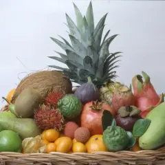 En korg fylld med exotiska frukter, inklusive en ananas som ser ut att vara redo att odla. Här finns även kokosnöt, kiwi, rambutan, granatäpple och mango.